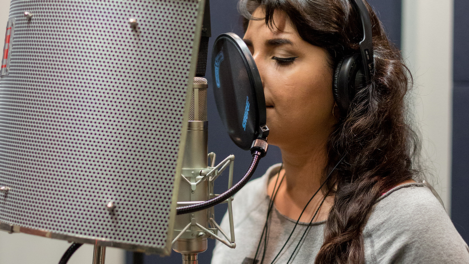 A woman singing into a microphone in a studio