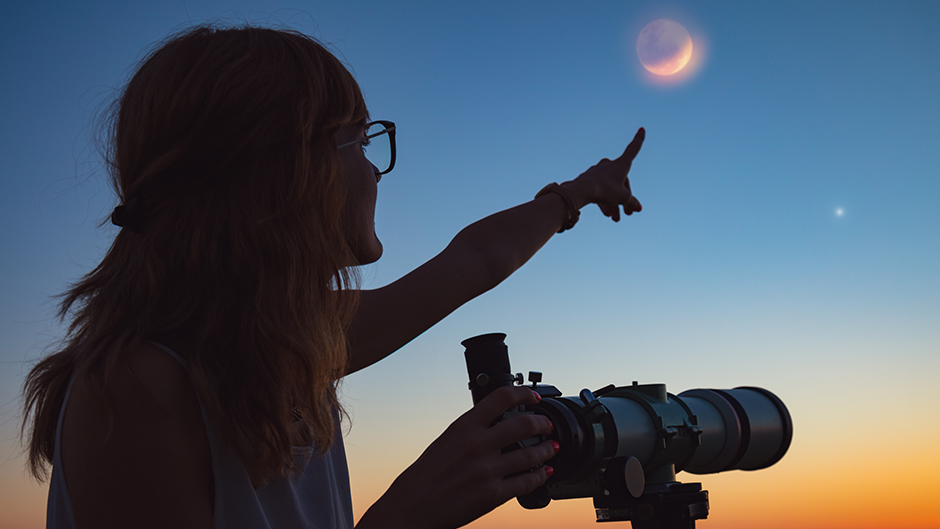Student with a telescope pointing at the night sky