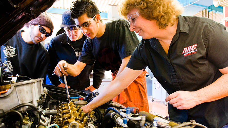 Students looking under the hood of an automobile